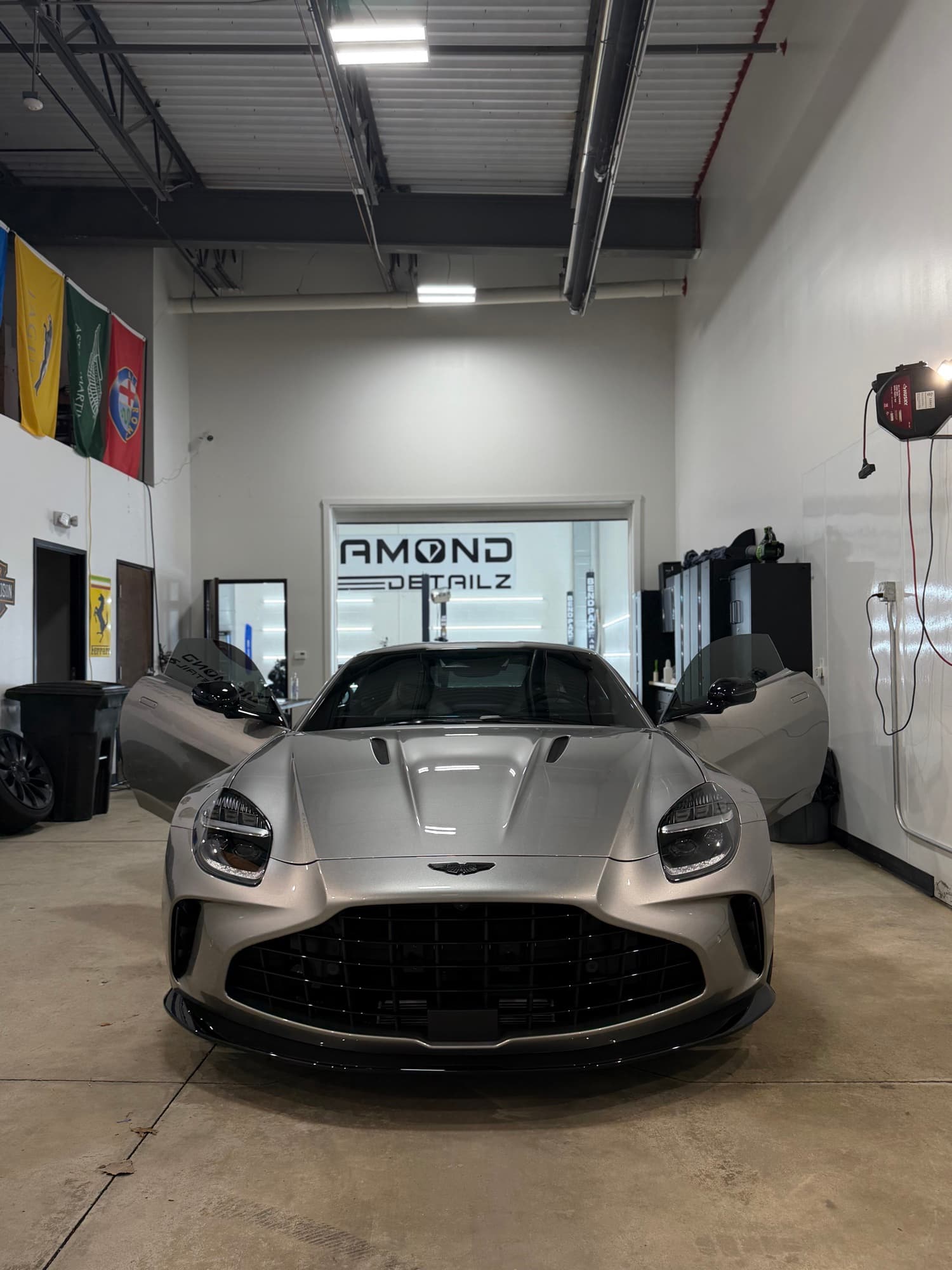 Silver Aston Martin Vantage in front of the Diamond Detailz shop sign