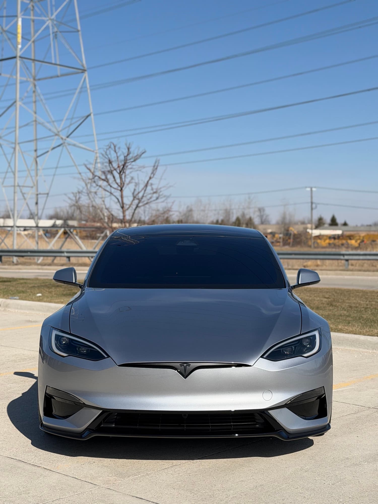 Silver Tesla Model S Plaid in pristine condition with Feynlab ceramic coating — mirror-finish silver paint, sharp reflections, clean panels in the same parking lot