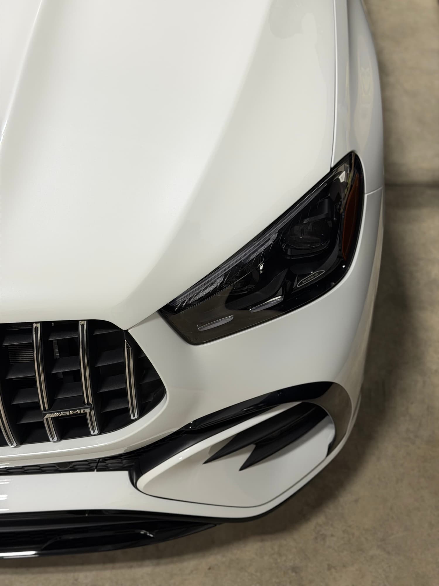 White Mercedes-AMG GT 4-door front detail with grille and AMG badge in the install bay