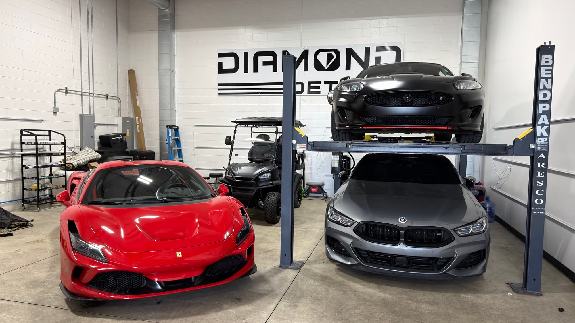 Red Ferrari F8, grey BMW M850i, and matte-black Jaguar XKR-S inside the Diamond Detailz shop